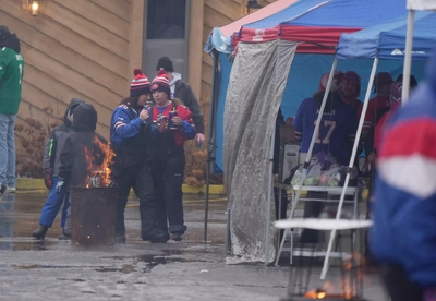 Not even continuous buckets of torrential rain can dampen the spirits of true Bills fans as they make the rounds of tailgate tents before the soggy game.