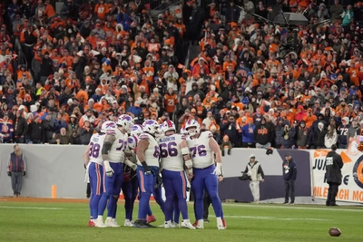 Bronco fans do their best NFL official imitation as they tauntingly wave brightly colored flags at the Buffalo Bills.
